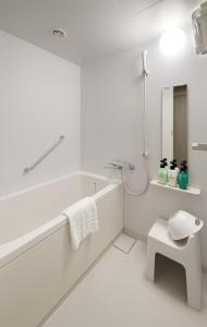 a white bathroom with a tub and a sink at Hotel Crown Hills Ueno Premier in Tokyo