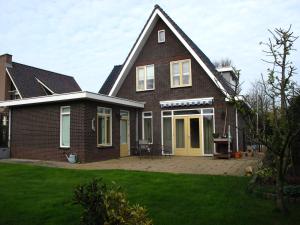 una casa de ladrillo marrón con puertas amarillas y un patio en B&B Limmerzand, en Limmen
