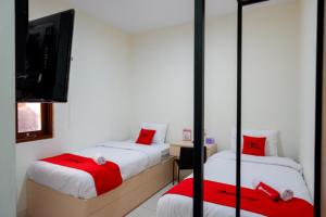 Ce lit se trouve dans un dortoir doté d'une télévision et d'un lit sidx sidx. dans l'établissement RedDoorz near Alun Alun Kudus 2, à Kudus