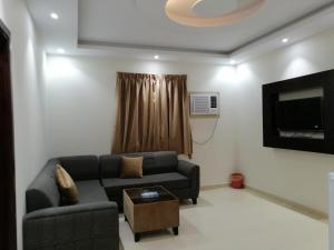 a living room with a couch and a tv at فخامه الارجوانه للشقق المخدومة in Sakakah