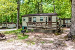 a tiny house in the woods with a porch at Williamsburg Camping Resort One Bedroom Cabin 6 in Croaker