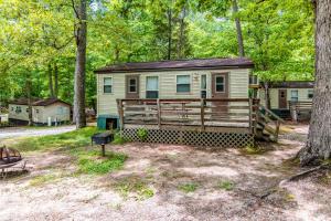 a tiny house in the woods with a porch at Williamsburg Camping Resort 28 ft. Park Model 11 in Croaker