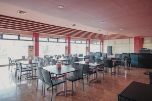 a dining room with tables and chairs and windows at RedDoorz Plus near Pelabuhan Merak in Cilegon