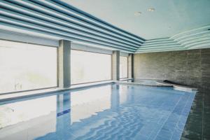 a large swimming pool with blue tiles and windows at RedDoorz Plus near Pelabuhan Merak in Cilegon