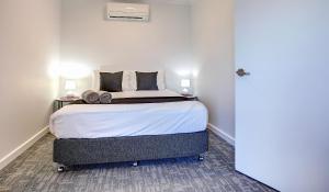 a bedroom with a large bed with two lamps on it at Limani Motel in Port Lincoln