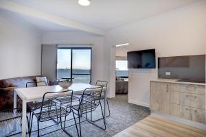 a kitchen with a table, chairs and a refrigerator at Limani Port Lincoln in Port Lincoln