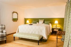 a bedroom with a bed and a chair and a mirror at Schloss Prielau Hotel & Restaurants in Zell am See