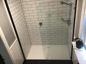 a shower with a glass door and white tile at Harrison House in Strahan