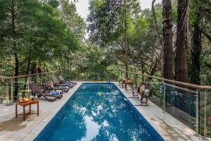 una piscina en una terraza con sillas y mesa en SaffronStays Odeon - art-deco heritage home with heated pool, private forest lawn and terrace, en Khandāla