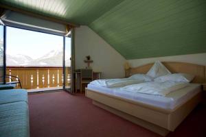 a bedroom with a bed and a large window at Hotel Pension Sonnenuhr in Tauplitz