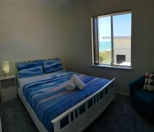 a bedroom with a bed with a teddy bear on it at Caravel Beach House Mandurah in Wannanup