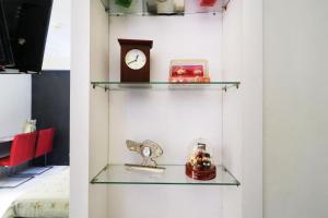 a glass shelf with a clock and other items on it at Apartment Kalibata City by Novi in Jakarta