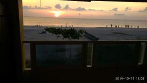 einen Blick aus dem Fenster eines Strandes mit Sonnenuntergang in der Unterkunft Alleppey Holiday Beach Resort in Alappuzha