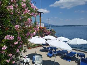 a group of white umbrellas and chairs next to the water at Hotel Milano in Belgirate