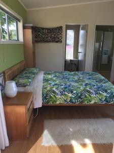 a bedroom with a bed with a green and blue bedspread at Chalet Cullen, in Mangawhai