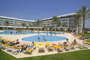 a group of people sitting in lawn chairs by a pool at Alfagar Alto da Colina in Albufeira