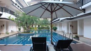 a swimming pool with two chairs and an umbrella at Gassan Legacy Golf Club in Lamphun