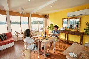 a man and woman sitting at a table in a room at Charter by DAE - Luxury River Cruise in Madapata