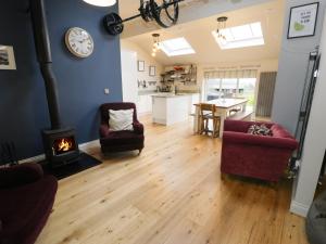 ein Wohnzimmer mit Kamin und einer Couch und Stühlen in der Unterkunft Horseshoe Cottage in Pwllheli