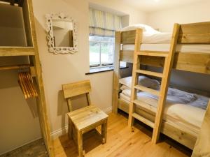 Zimmer mit 3 Etagenbetten und einem Spiegel in der Unterkunft Horseshoe Cottage in Pwllheli