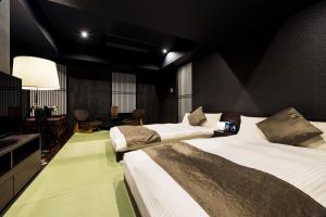 a hotel room with two beds and a television at PROSTYLE Ryokan Yokohama Bashamichi in Yokohama