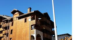 a tall brick building with a blue sky in the background at Joli petit appartement cosi 5 personnes maxi plein centre station les deux alpes in Les Deux Alpes