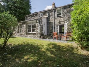 ein Cottage aus Stein mit einem Tisch und Stühlen auf einem Rasen in der Unterkunft Stair Cottage in Keswick