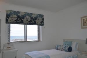 a bedroom with a bed and a window with a curtain at Beach Villa Apartment in Hermanus +7 photos