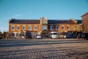 a large orange building with cars parked in front of it at Hotel Staroyamskaya in Torzhok