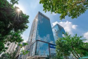 un alto edificio di vetro con il sole nel cielo di 深圳金中环服务公寓-深业上城店 Golden Central Serviced Residence Shenzhen-UpperHills a Shenzhen