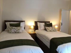 two beds in a room with two lamps on tables at Millcroft in Penrith