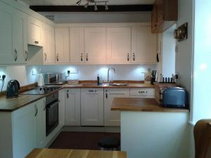 uma cozinha com armários brancos e um lavatório em Millcroft em Penrith