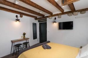 a bedroom with a yellow bed and a tv at Private Accommodion Linda Studio in Dubrovnik