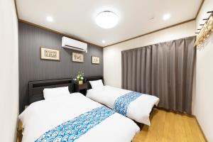 a bedroom with two beds and a curtain at Shirakabanoyado - Nakamichi in Osaka
