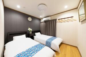 a bedroom with two beds and a clock on the wall at Shirakabanoyado - Nakamichi in Osaka