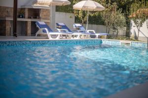 a swimming pool with blue chairs and umbrellas at Apartments Gvozdenovic in Herceg-Novi