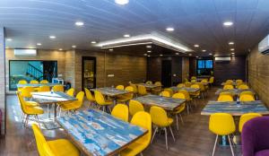 una sala da pranzo con tavoli e sedie gialle di IKHAYA HOTELS a Nuova Delhi