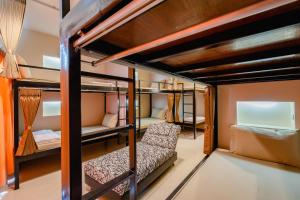 a room with bunk beds with a couch and a chair at Restiny Hostel in Bangkok
