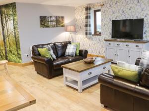 a living room with leather furniture and a flat screen tv at Woodman's Lodge in Nantwich