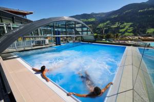 zwei Personen schwimmen in einem Pool auf einem Gebäude in der Unterkunft Appartements Pungg in Fügen