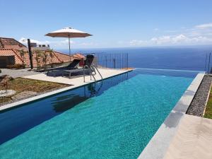 a swimming pool with a chair and an umbrella at Casa Atlantico tropischer Seitenflügel in Ribeira Brava