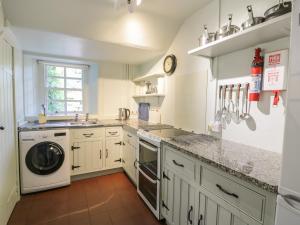 uma cozinha com armários brancos e uma máquina de lavar e secar roupa em Near Bank Cottage em Eyemouth