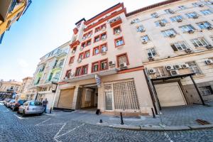 een hoog gebouw in een straat met geparkeerde auto's bij Sofia Industrial Life Apartment in Sofia