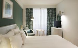 リスボンにあるAltis Suites Apartamentos Turísticosのベッドとテレビ付きのホテルルーム
