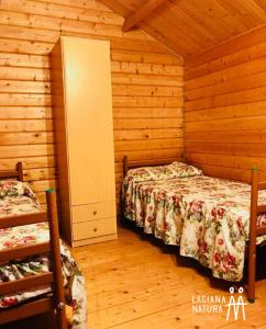 1 dormitorio con 2 camas en una cabaña de madera en Camping Laciana Natura, en Villablino