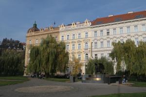 Hotel Klarinn Prague Castle في براغ: مبنى كبير امامه تمثال