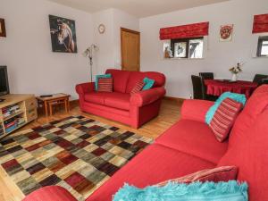 a living room with red furniture and a red couch at Stables Cottage in Llanrwst