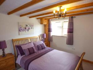 ein Schlafzimmer mit einem Bett mit lila Kissen und einem Fenster in der Unterkunft Copper Beech Cottage in Coniston