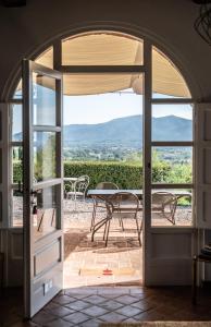 una puerta que conduce a un patio con mesa y sillas en Casale rinnovato immerso nella campagna con splendida piscina privata, en Capannori
