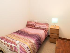 a bedroom with a bed and a night stand with a lamp at Bryn Eithin in Blaenau-Ffestiniog